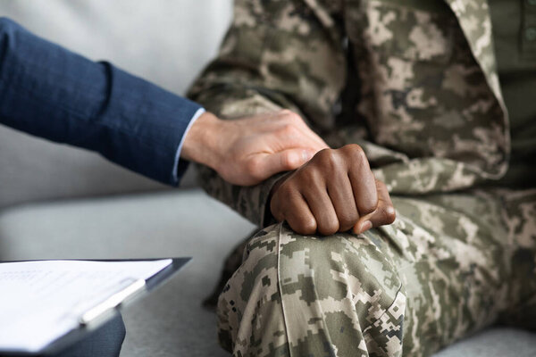 Unrecognizable psychologist comforting military man during session, cropped