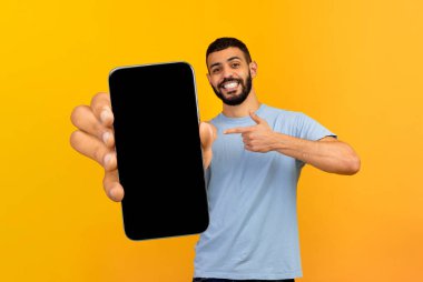 Mutlu adam akıllı telefonu siyah ekranla sunuyor, alete doğrultuyor.