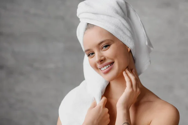 홈 스킨 케어 컨셉. 수건을 머리에 쓰고 카메라 앞에서 웃으며 완벽 한 피부를 가진 아름다운 여인의 모습 — 스톡 사진