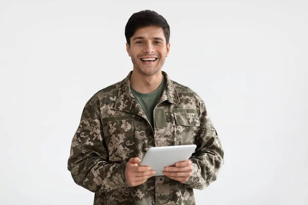 Hombre sonriente en uniforme de camuflaje sosteniendo tableta digital — Foto de Stock