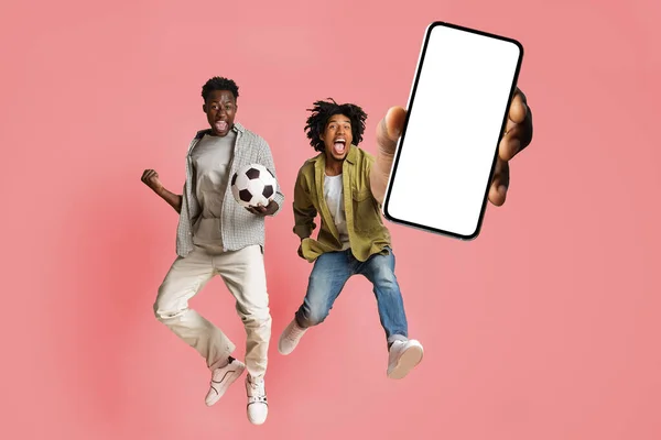 男性朋友欢欣鼓舞地跳起来，用空白的白屏展示着大大的智能手机，模仿着拼贴的横幅 — 图库照片