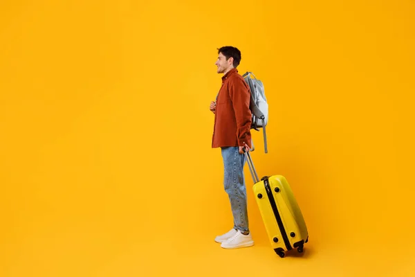 Podróżnik z walizką podróżną i plecakiem na żółtym tle — Zdjęcie stockowe