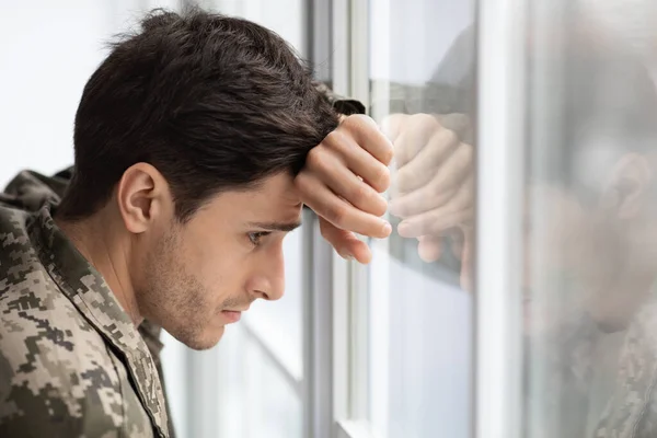 Καταπιεσμένος στρατιώτης κοιτάζει μέσα από το παράθυρο στο σπίτι — Φωτογραφία Αρχείου
