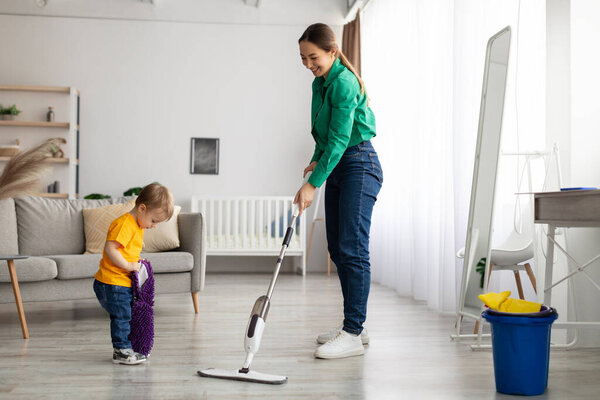 Helping hand. Little toddler boy helping mother doing the cleaning, mom looking at child and smiling