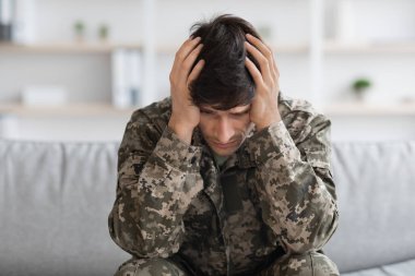 Depresyondaki asker kafasını avuç içiyle örtüyor.