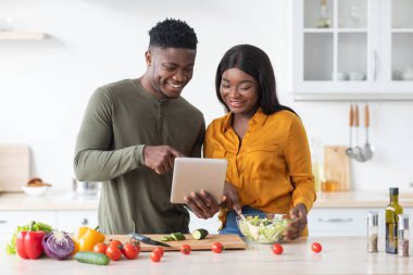 İnternetten yemek tarifi. Mutfakta Yemek Yaparken Dijital Tablet Kullanan Mutlu Siyah Eşler