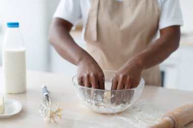 Bin yıllık Afrika kökenli önlüklü Amerikalı kadın mutfaktaki masada hamur yapıyor, kapat.