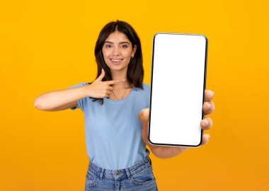 Elinde boş ekranlı akıllı telefon tutan mutlu kadın, aleti işaret ediyor.