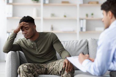 Hüsrana uğramış kamuflajlı bir adam psikologla konuşuyor.