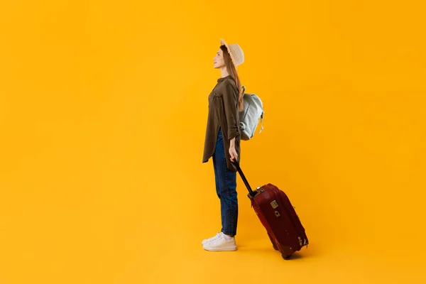 Turista femenina con maleta y equipaje de pie sobre fondo amarillo — Foto de Stock