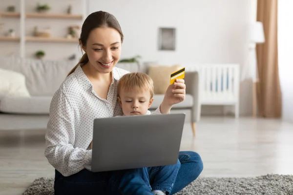 Легкие выплаты. Счастливая молодая мама и ее ребенок с ноутбуком и кредитной картой. — стоковое фото