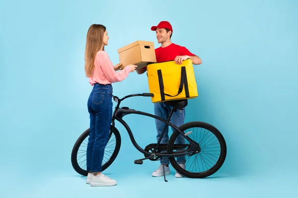 Deliveryman che dà la scatola del pacchetto del cartone alla donna sopra sfondo blu — Foto Stock