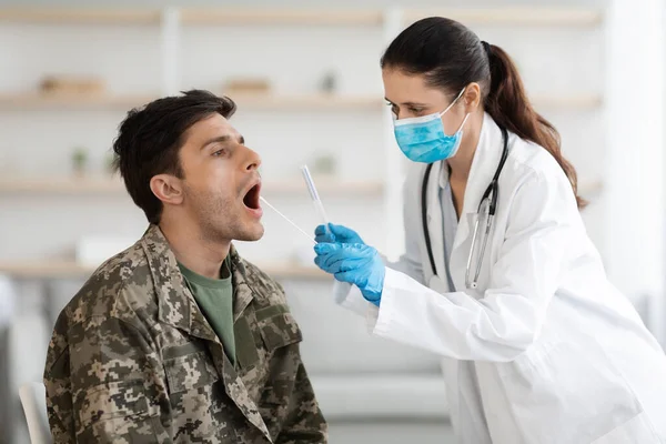Doktor odebírá vzorek na test DNA vojákovi na klinice. — Stock fotografie