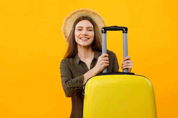 Alegre dama turista posando con maleta usando sombrero, fondo amarillo — Foto de Stock