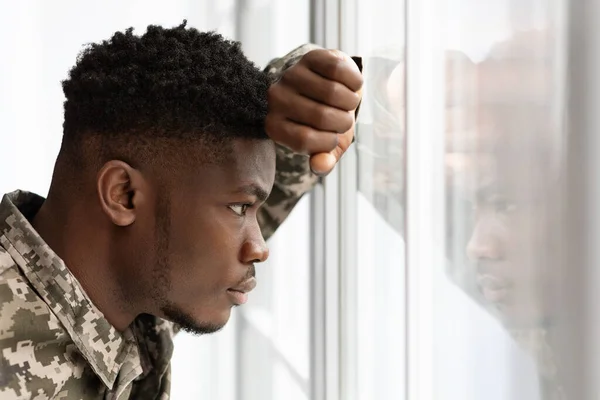 Pensive africký americký voják dívá oknem doma — Stock fotografie
