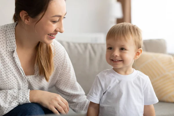 Feliz joven madre caucásica disfrutando del tiempo con su hijo, mirando al hijo y sonriendo, jugando juntos en casa —  Fotos de Stock