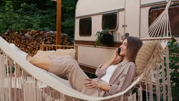 Mulher bonita deitada em rede e conversando no celular no acampamento — Vídeo de Stock