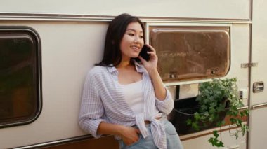 Modern Trailer 'ın yanında dikilen Güzel Asyalı Kadın Cep Telefonuyla Konuşuyor