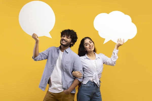 Joven pareja india sosteniendo burbujas de voz vacías con espacio libre para su texto en el fondo del estudio amarillo — Foto de Stock