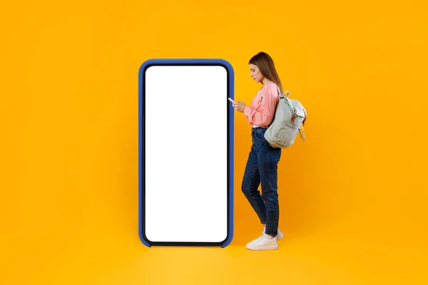 Donna turista utilizzando Smartphone in piedi vicino a grande cellulare, sfondo giallo — Foto Stock