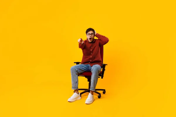 Shocked Man Pointing Finger At Camera Sitting Over Yellow Background — Stock Photo, Image