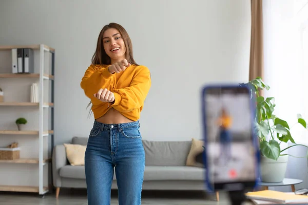 Joven mujer caucásica influencer grabación de vídeo en el teléfono inteligente, bailando en la cámara en casa — Foto de Stock