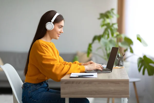 Młoda biała dama w słuchawkach za pomocą laptopa, pracująca online z domu, przestrzeń do kopiowania — Zdjęcie stockowe