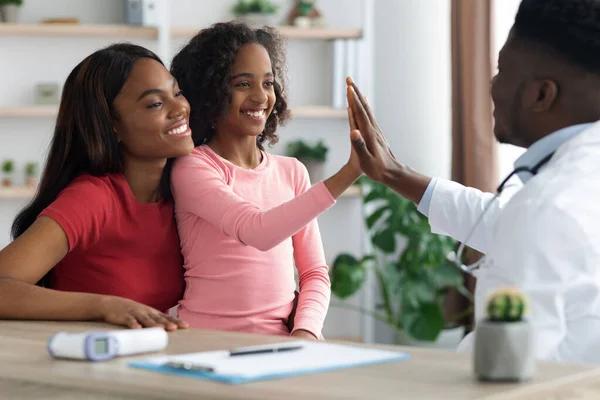 African american mother and daughter at appointment with doctor