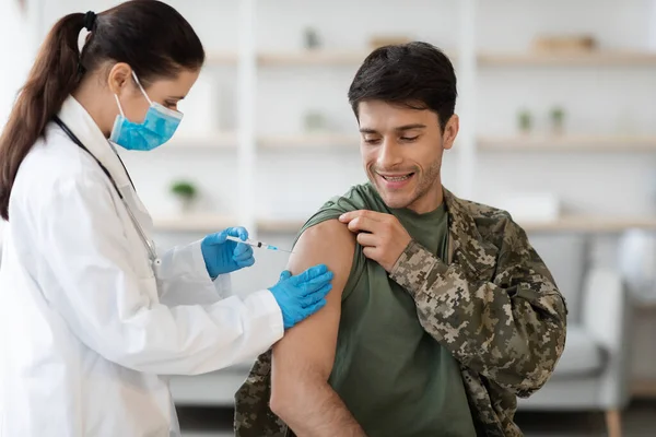 Веселий солдат отримує імунізацію від коронавірусу в клініці — стокове фото