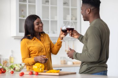 Genç ve romantik siyah eşler Mutfakta şarap içip yemek pişiriyor