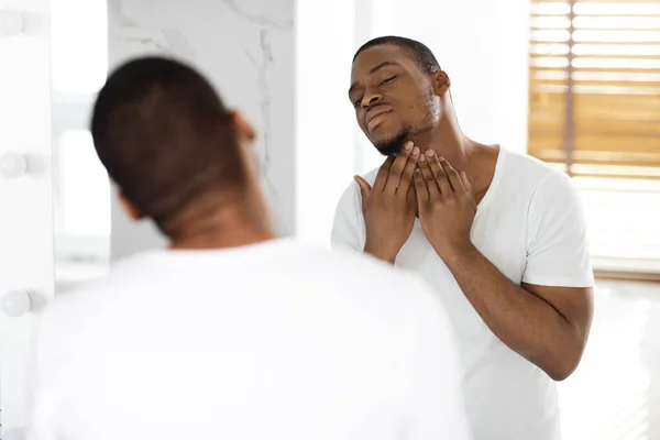 Problémy s vlasy. Portrét neoholeného černocha dotýkajícího se krku se štětinkou — Stock fotografie