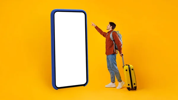 Turista chico usando enorme celular con pantalla vacía, fondo amarillo — Foto de Stock