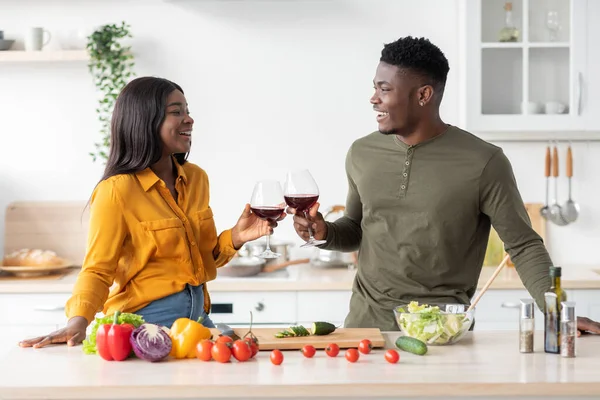 Afectuosa pareja negra bebiendo vino tinto en la cocina mientras preparan el almuerzo juntos — Foto de Stock