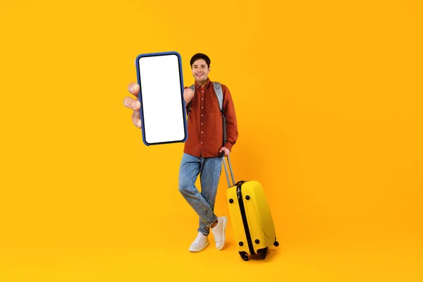 Чоловік турист показує смартфон порожній екран стоячи над жовтим тлом — стокове фото