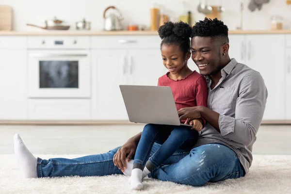 Счастливые чернокожие отец и дочь вместе пользуются ноутбуком дома — стоковое фото