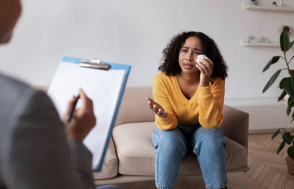 Giovane donna afroamericana che piange in sessione con lo psicologo, parlando con il professionista della salute mentale in ufficio — Foto Stock