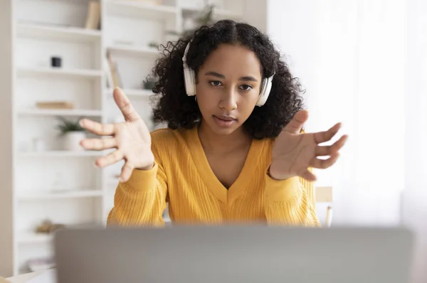 Jovem afro-americana em fone de ouvido tendo reunião on-line no computador portátil em casa — Fotografia de Stock