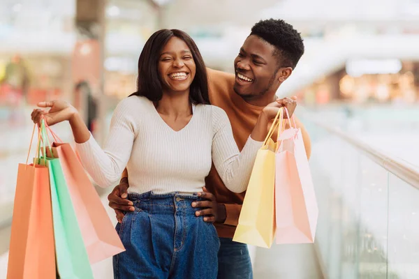Retrato de pareja negra emocionada caminando con bolsas de compras —  Fotos de Stock