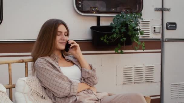 Красивая молодая женщина разговаривает по мобильному телефону во время отдыха на открытом воздухе в кемпинге — стоковое видео