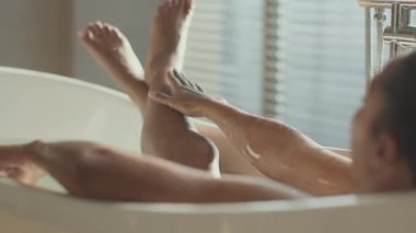 Kadın gevşemesi. Omzunun üzerinden, genç Afrikalı Amerikalı bayanın banyoda rahatlamasını, mükemmel ıslak vücudu okşamasını, boş uzayı.