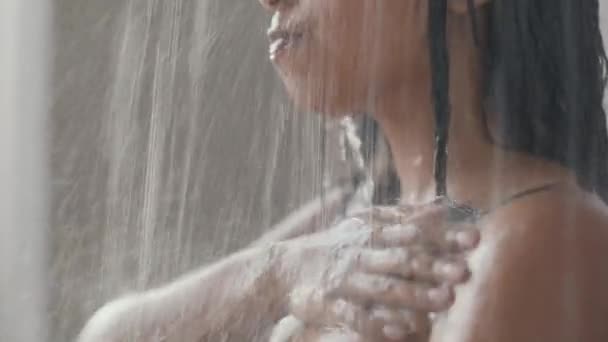 Ung oigenkännlig svart kvinna tar dusch, tvätta sin perfekta kropp under vattendroppar, spårning skott, fritt utrymme — Stockvideo
