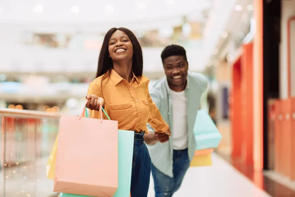Opgewonden zwarte vrouw trekken man naar winkel — Stockfoto