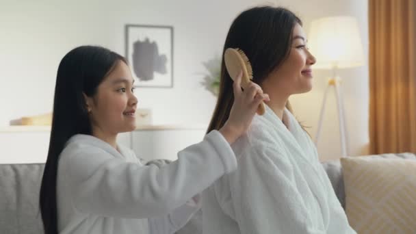 Journée beauté à la maison. Petite fille asiatique mignonne brossant ses cheveux de mères, jouant coiffeur à la maison, vue latérale — Video