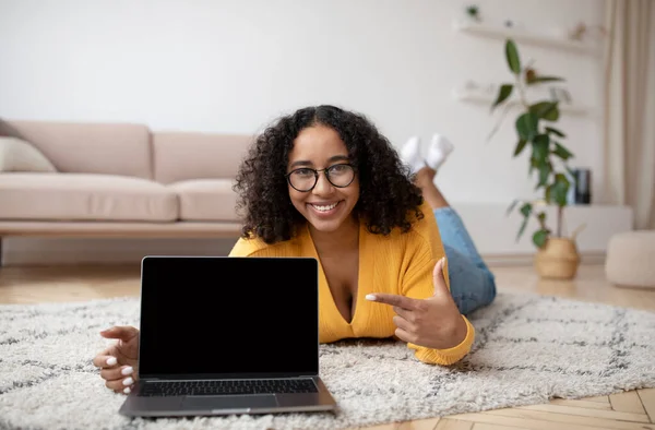 Jovem Alegre Mulher Negra Deitada Chão Apontando Para Computador Portátil — Fotografia de Stock