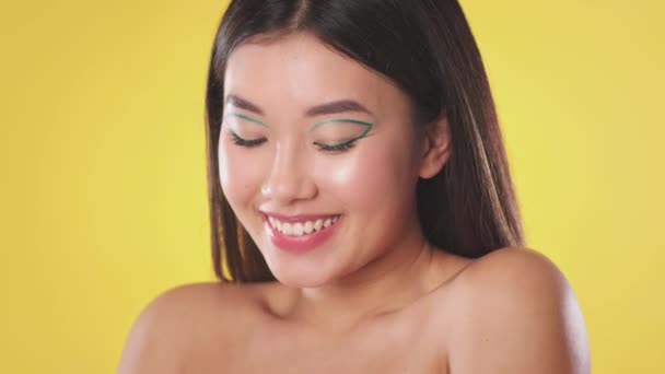 Jovem mulher asiática positiva com criativo compõem e ombros nus sorrindo para a câmera, câmera lenta — Vídeo de Stock