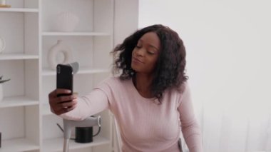 Koltuk değnekleriyle evde selfie çeken mutlu Afrikalı Amerikalı kadın.