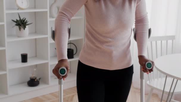 Dame noire méconnaissable marchant avec des béquilles à l'intérieur, recadrée — Video