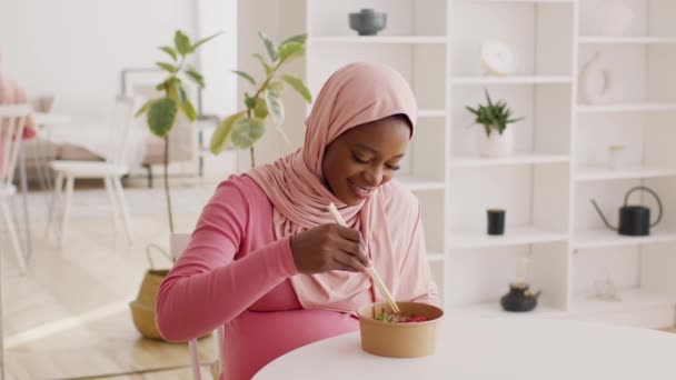 Embarazada afroamericana dama usando hijab comer ramen en casa — Vídeo de stock