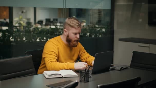 Bärtiger männlicher Unternehmer mit Laptop arbeitet online im Büro — Stockvideo