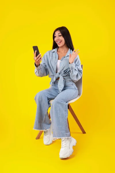 Cheerful woman having video call using cellphone and waving — Stock Photo, Image